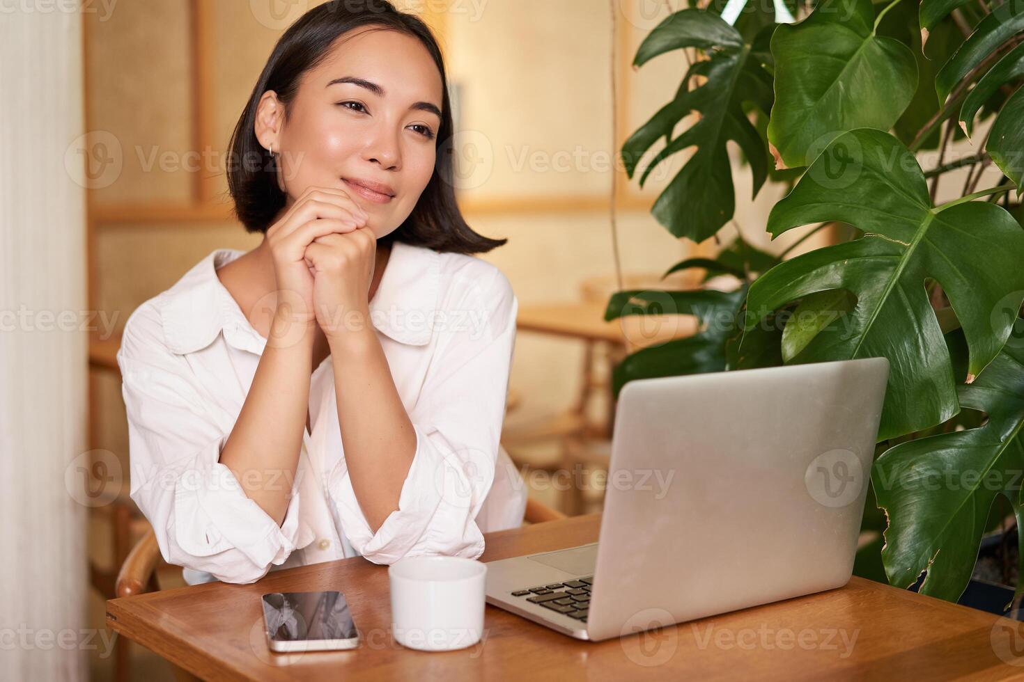 Beautiful brunette girl with laptop, sitting in cafe, working remotely, freelancing while sitting in coworking space photo
