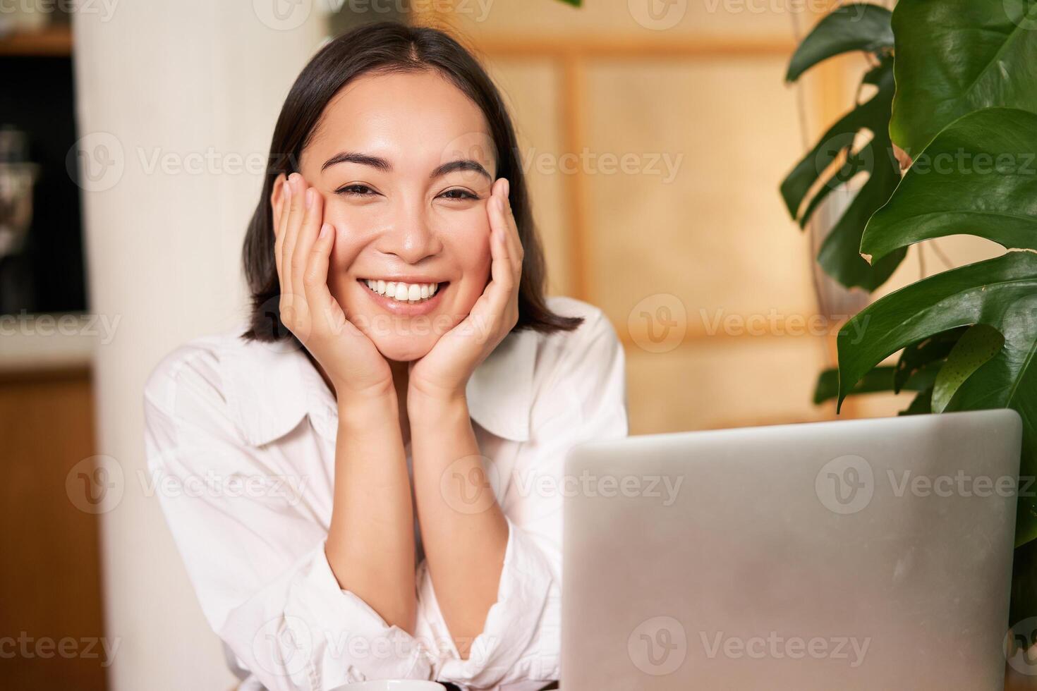 Beautiful young woman with happy smile, sitting in cafe with laptop, studying remotely, working online from distance photo
