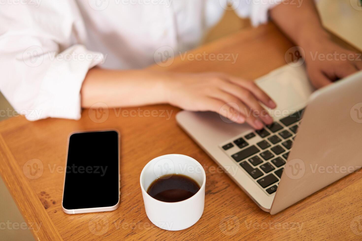 Cropped shot of female hands typing on laptop keyboard, drinking coffee, working in cafe, studying, doing homework photo