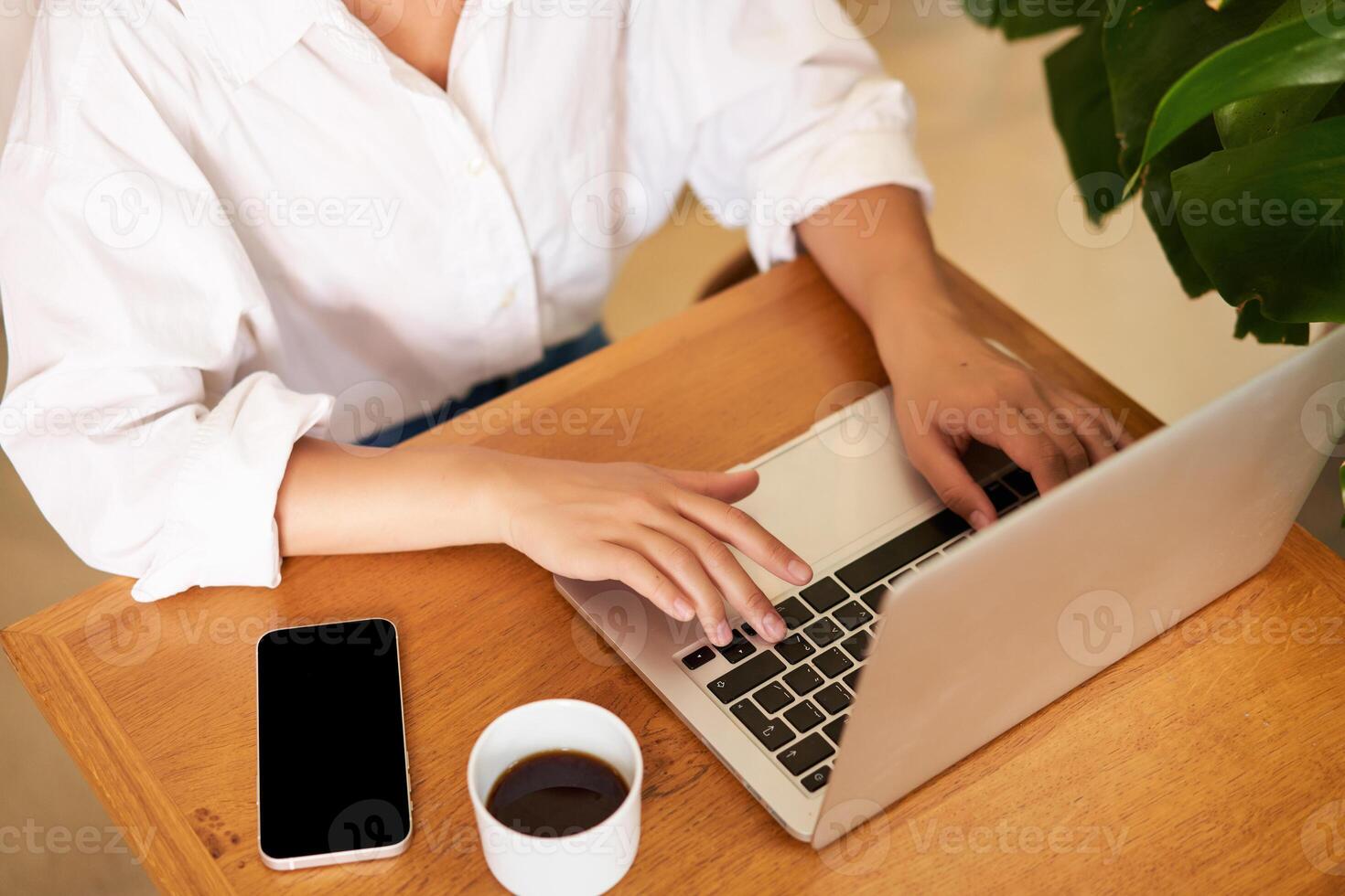 Cropped shot of female hands typing on laptop keyboard, drinking coffee, working in cafe, studying, doing homework photo