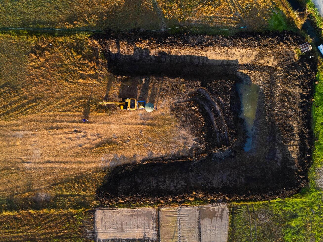 Excavating dirt into a dump truck to build a water storage pond for use in the dry season for agriculture. Aerial view of a backhoe is working. photo