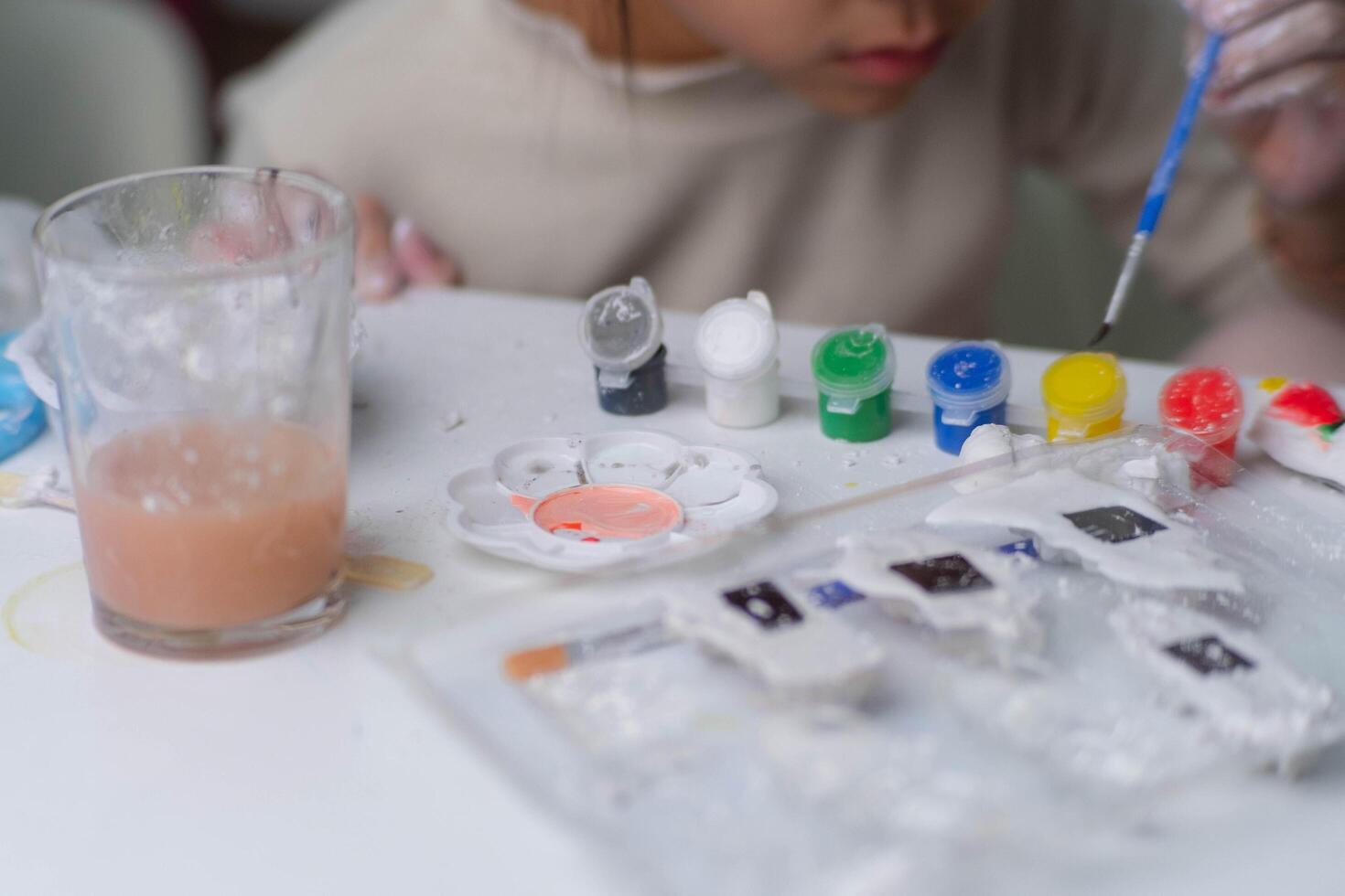 Cute little girl making DIY plaster and painting at home. Close-up of children painting on plaster sculpture with family on holiday. Imagination and creativity activities. photo