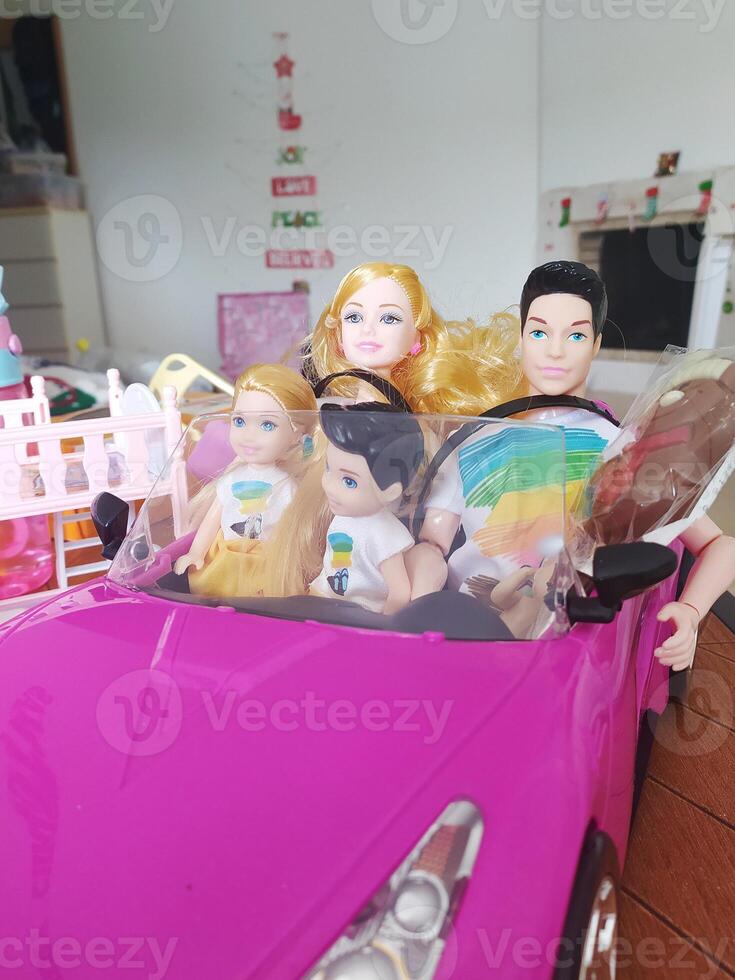 muñeca familia mamá, papá y niños en un juguete rosado coche. Navidad presente. foto