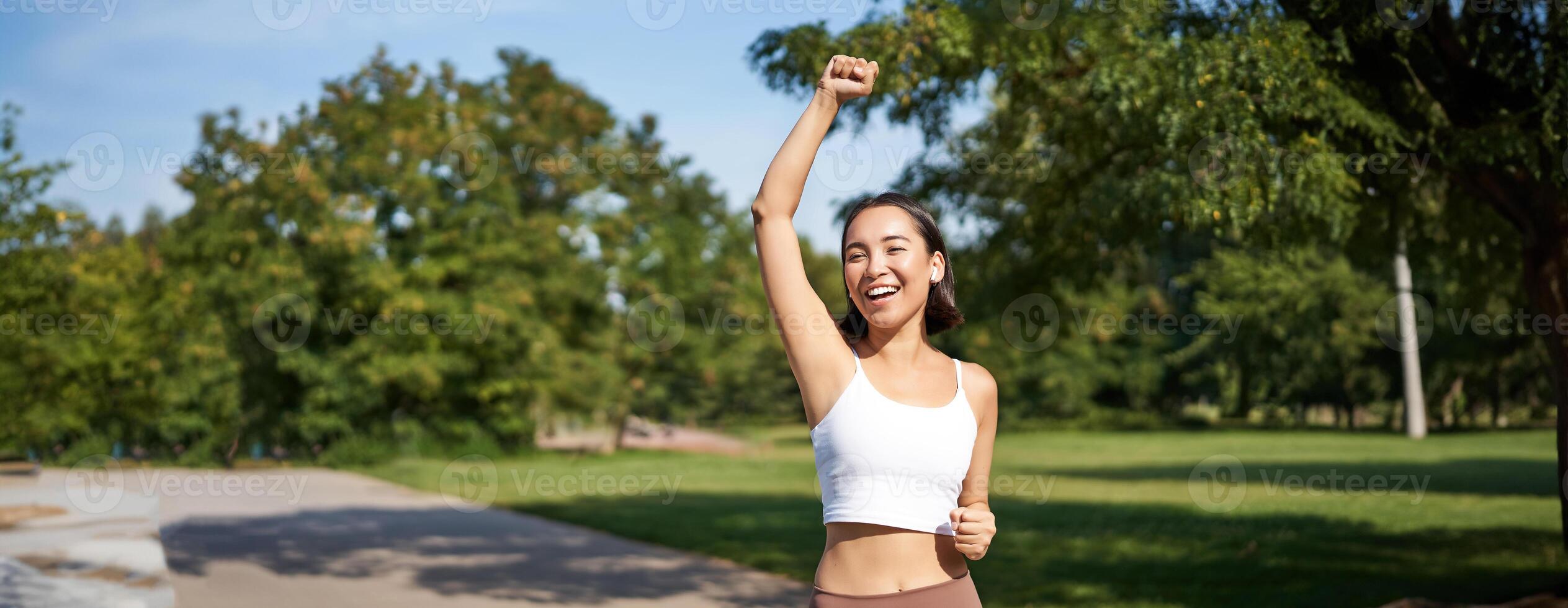 Hooray, victory. Smiling asian girl triumphing, celebrating achievement, running till finish, shouting from excitement photo