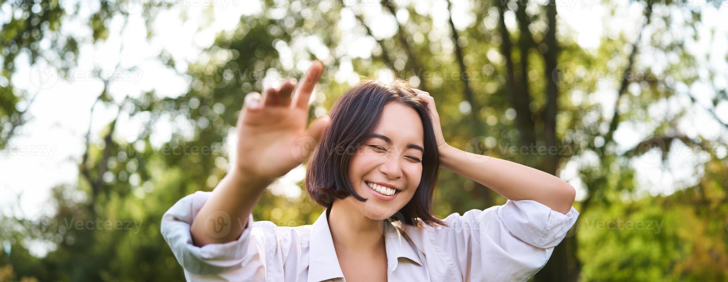 personas y emociones concepto. contento asiático mujer riendo y sonriente, posando en verano día en parque foto