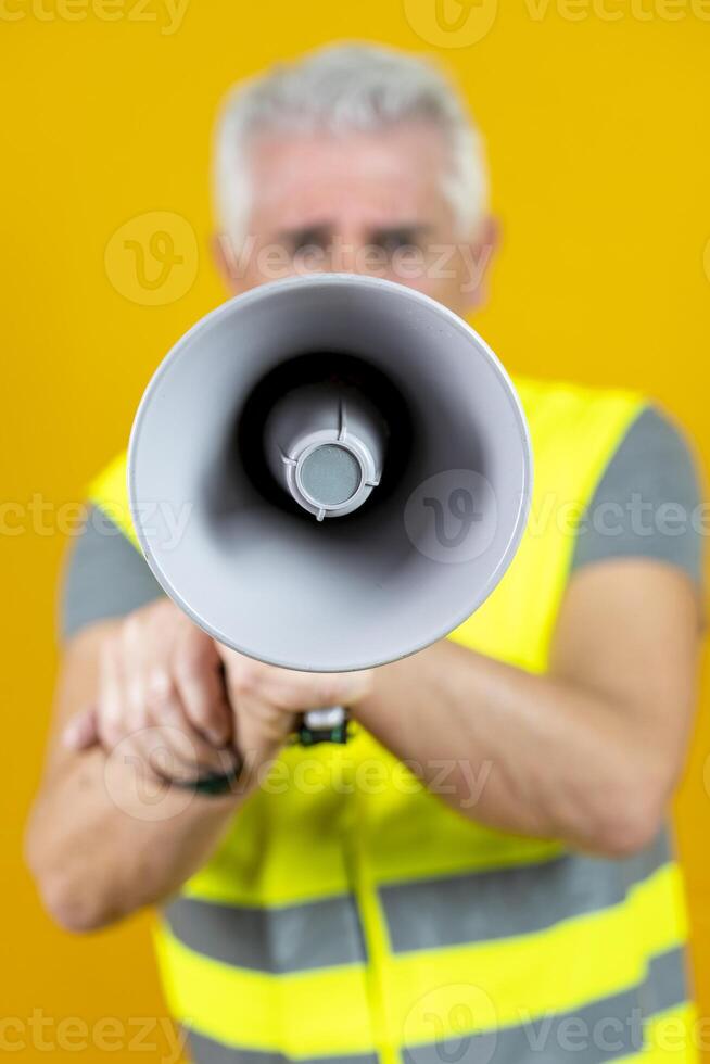 mature worker screaming into megaphone isolated on yellow background photo