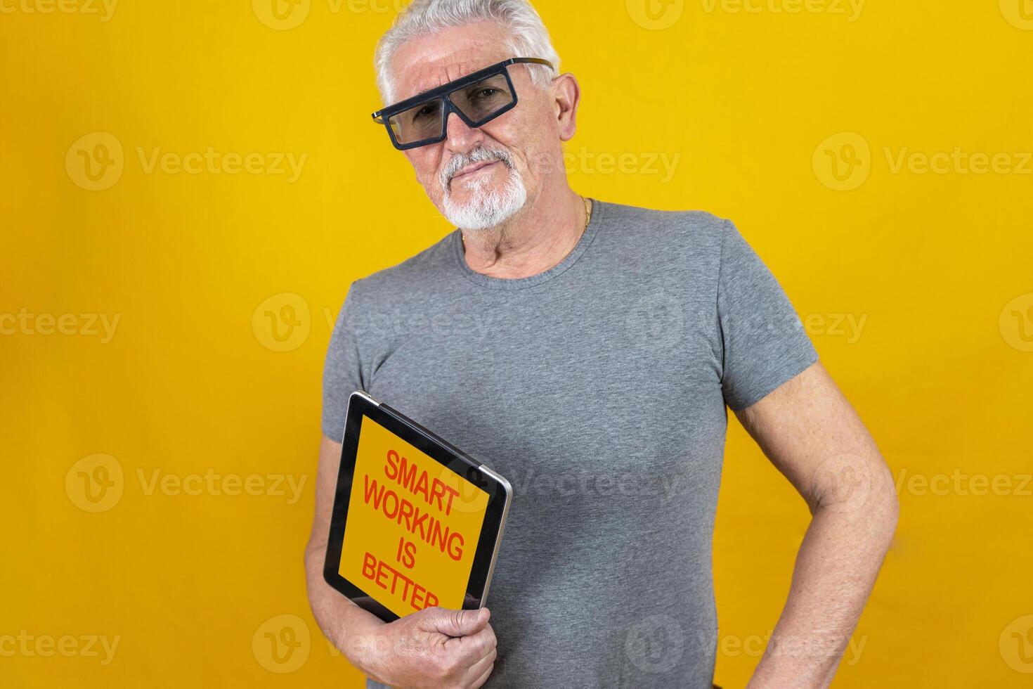 portrait of a mature worker shows a tablet isolated on yellow background photo