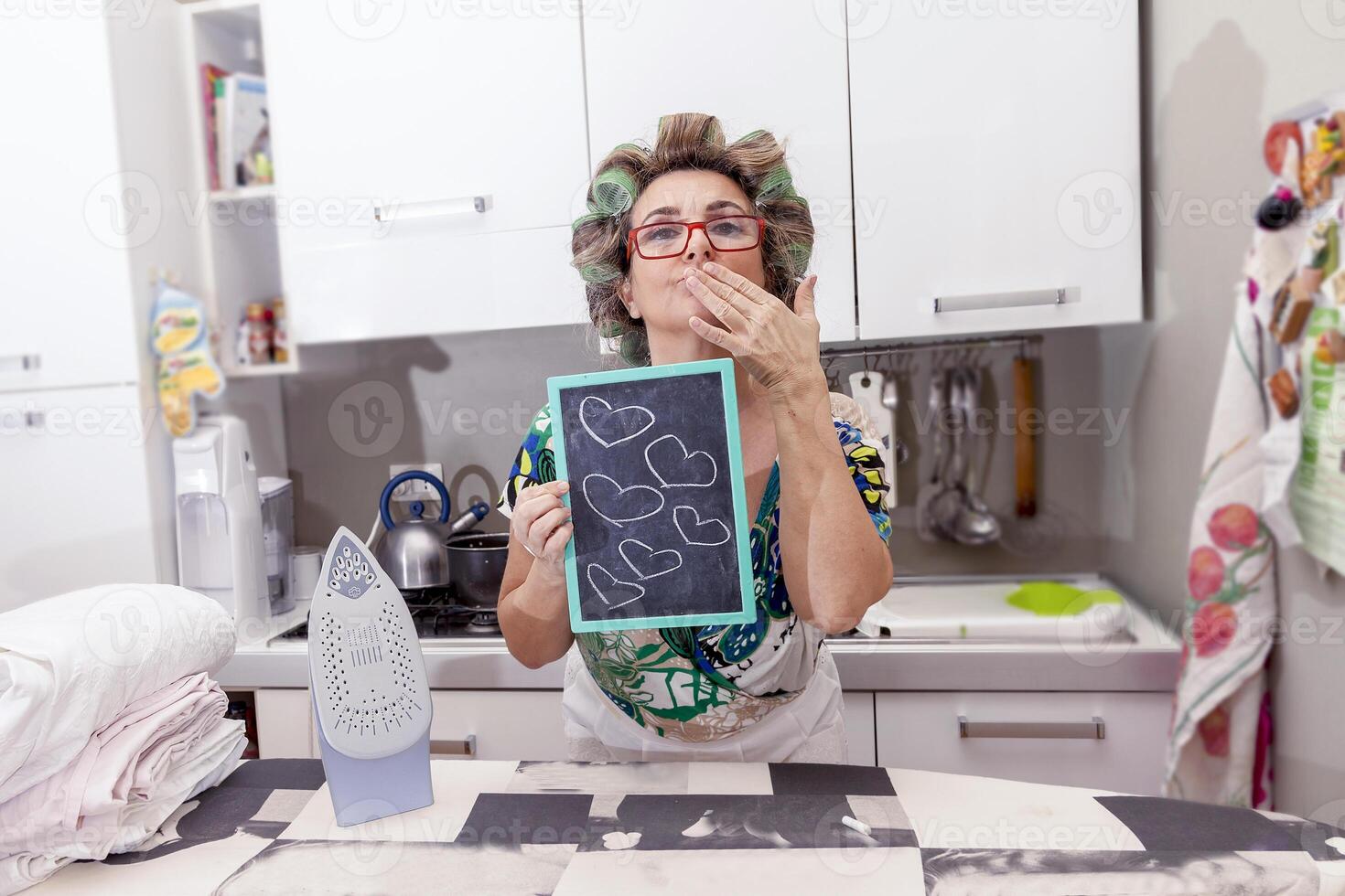 mature housewife woman with curlers shows a board with hearts photo