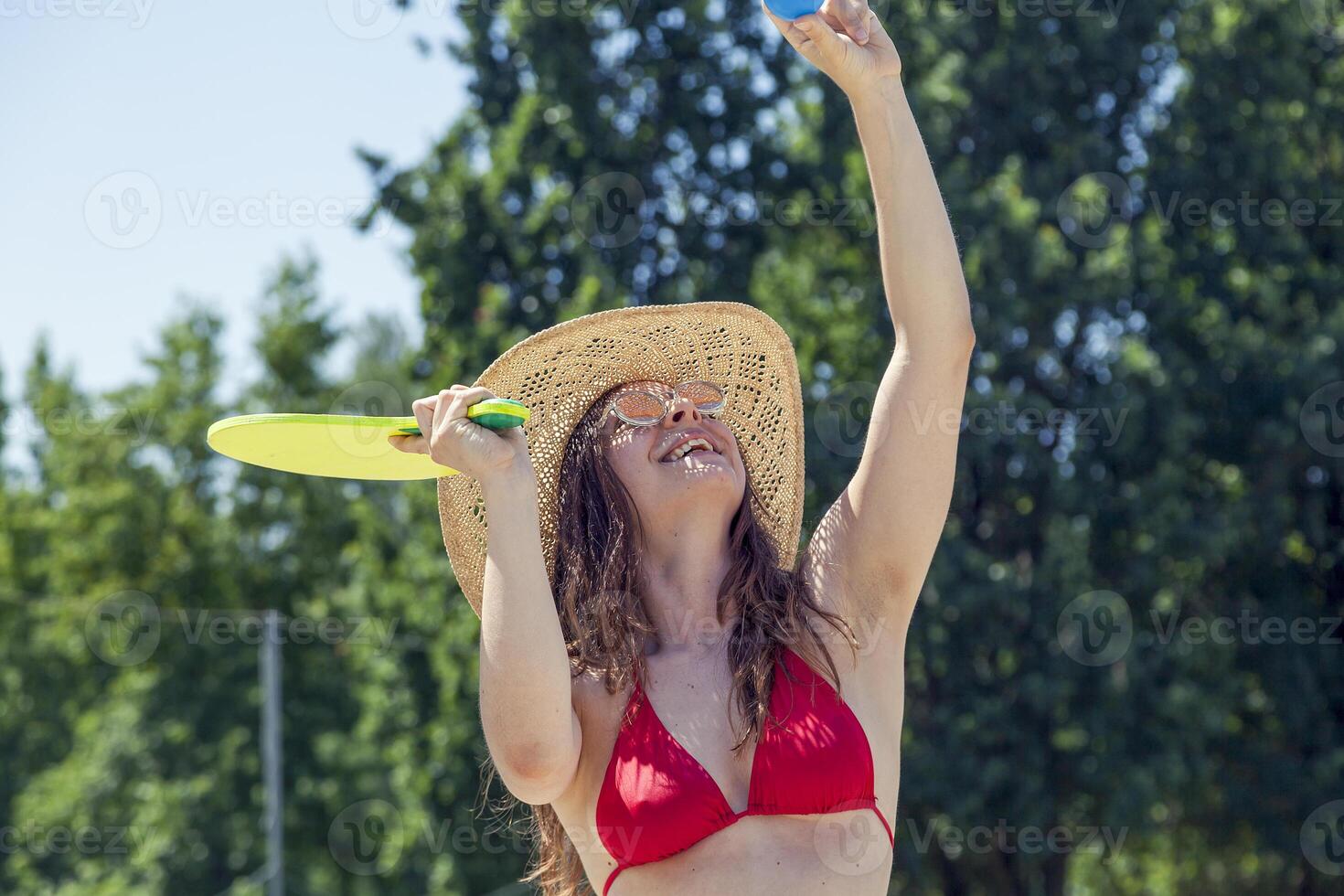 Young adult woman playing tennis on the beach photo