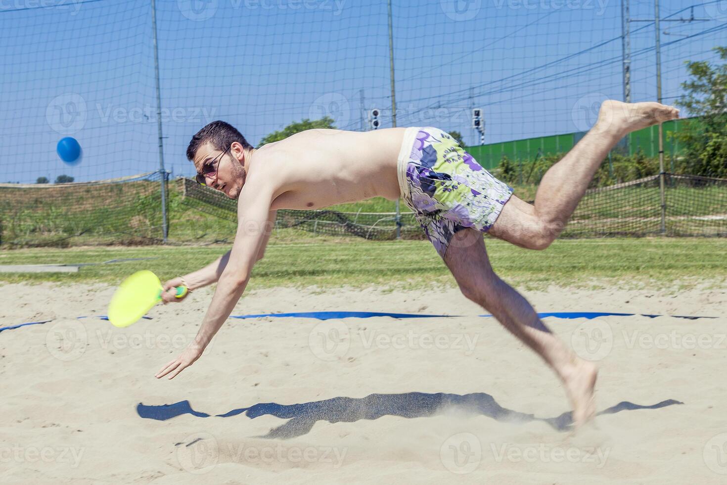 Young adult man plays tennis on the beach photo