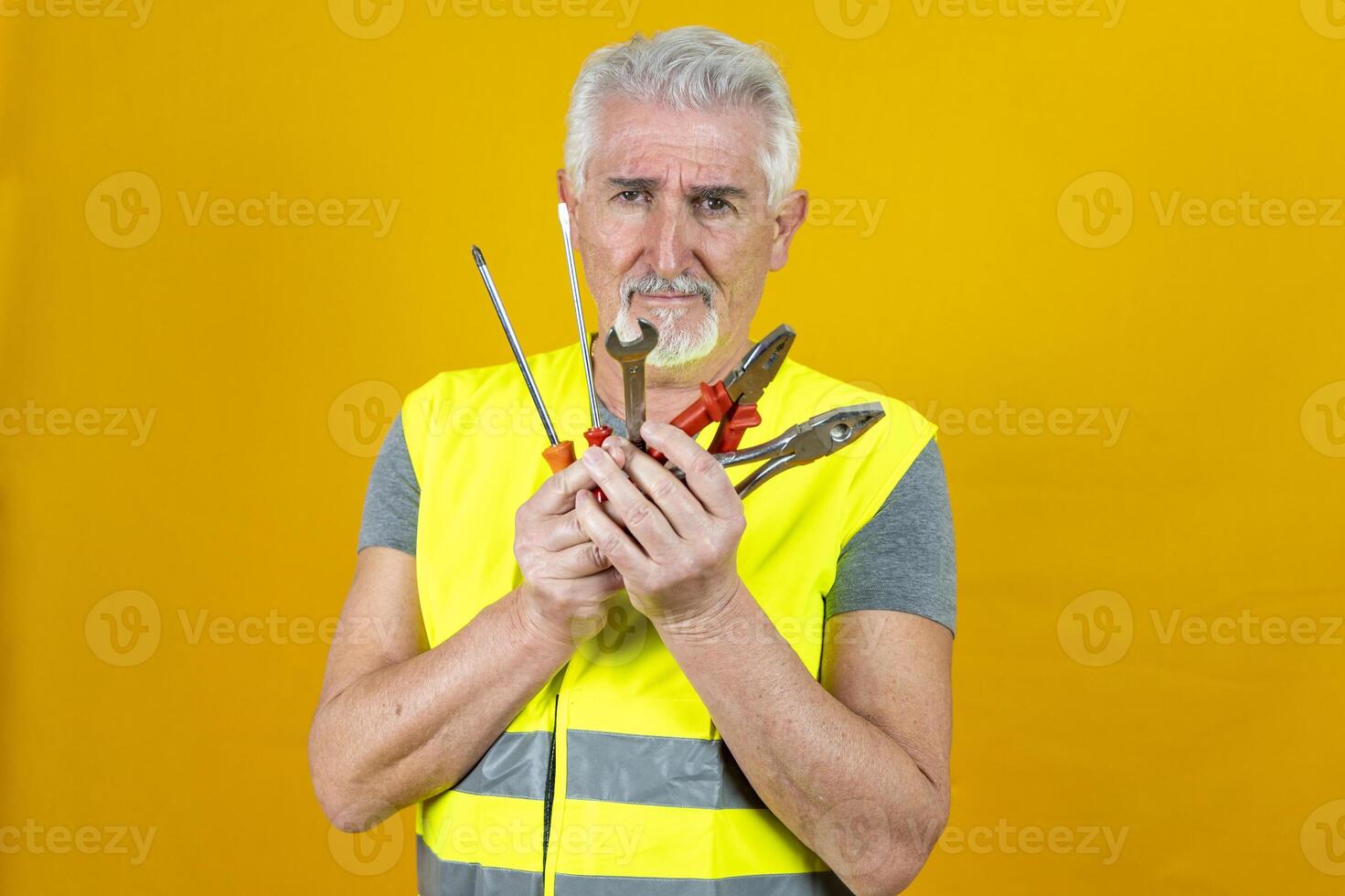 portrait of a mature worker wearing reflector vest isolated on yellow background photo