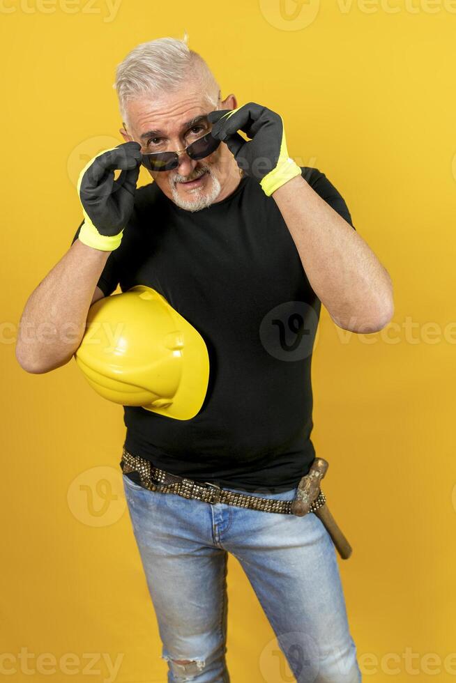 worker with helmet and gloves isolated on yellow background photo
