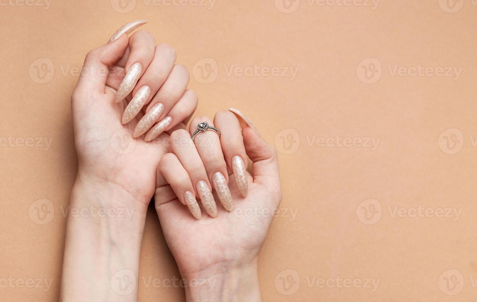 Hand on a brown background and beautiful pearl manicure close up photo
