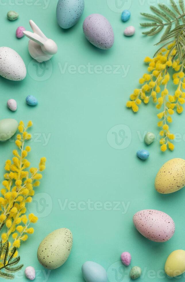 Festive Easter Decoration With Colorful Eggs and Mimosa Flowers on a Pastel Green Background photo