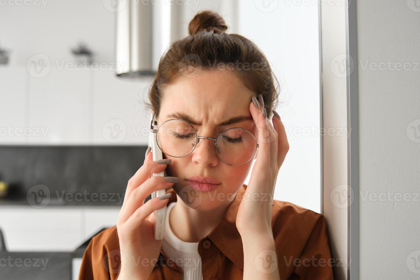Close up portrait of young troubled, worried woman listens to voice message, having difficult phone conversation, answer a call and looking concerned, touching head photo