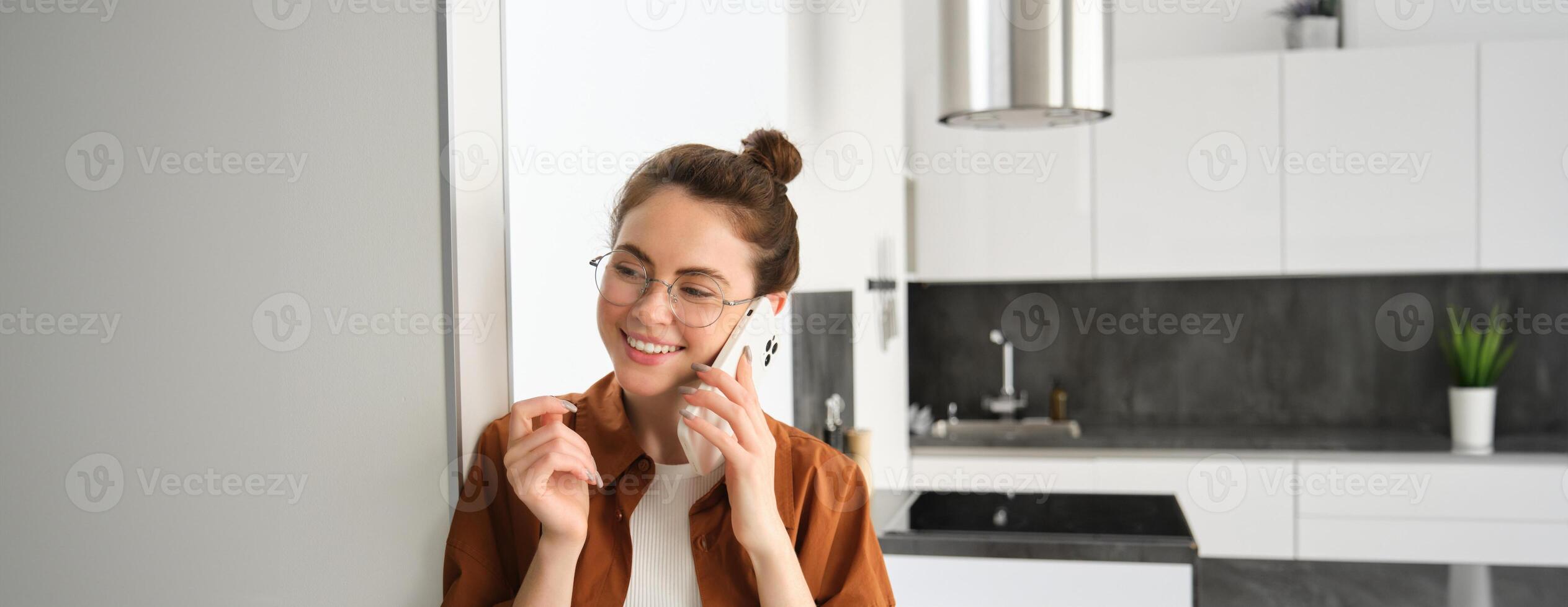 Portrait of happy woman at home, answers phone call, talking on mobile, holding smartphone and smiling photo