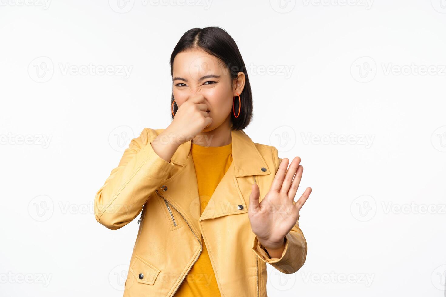 Image of asian girl shuts nose and reject smth with disgusting bad smell, shuts nose, standing over white background photo