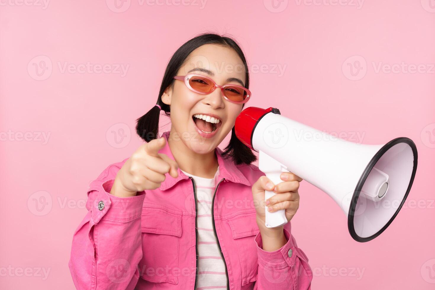 Attention, announcement concept. Enthusiastic asian girl shouting in megaphone, advertising with speaker, recruiting, standing over pink background photo