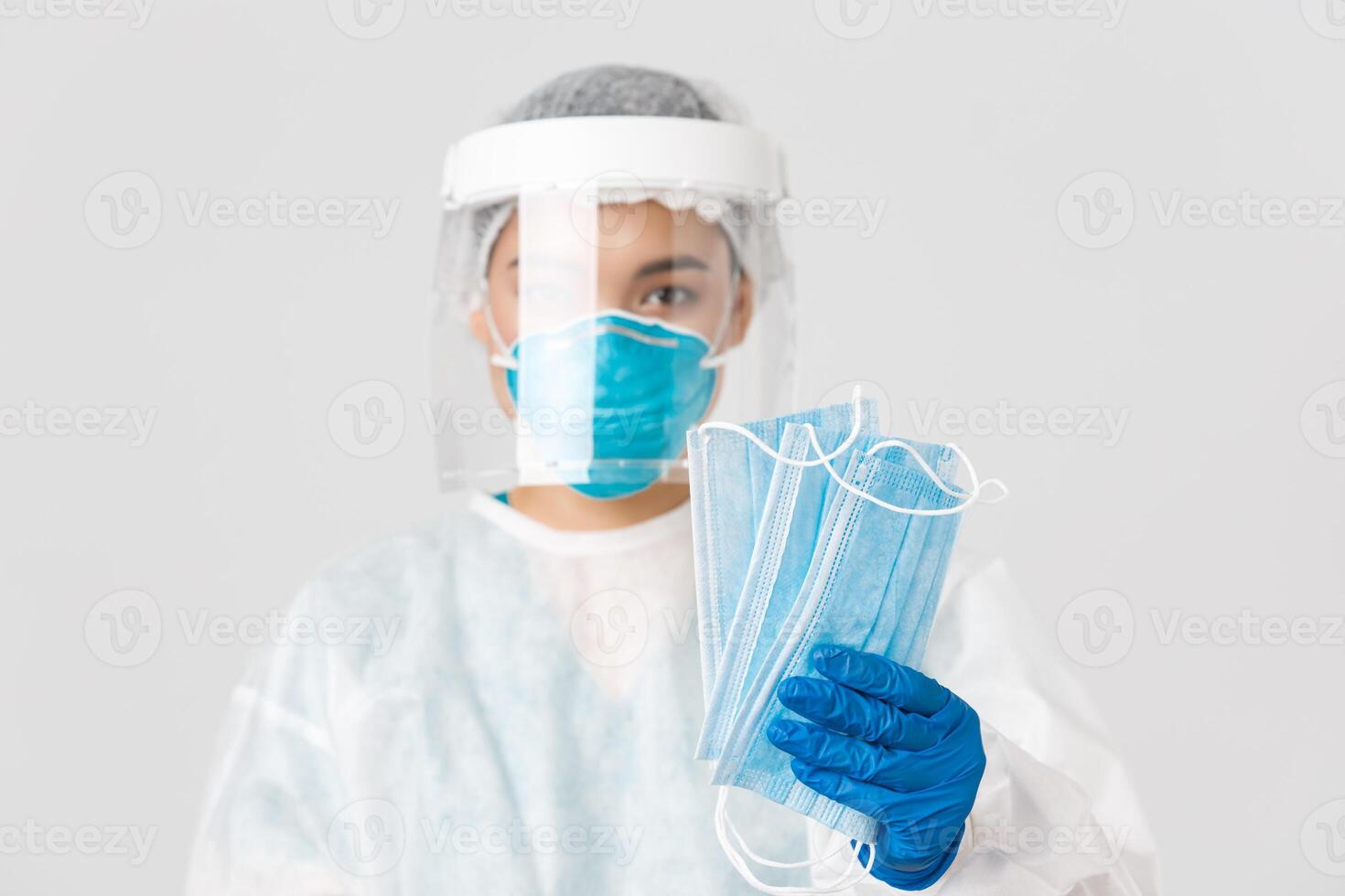 Covid-19, coronavirus disease, healthcare workers concept. Close-up of female asian doctor in personal protective equipment give patients medical masks to ensure safety, white background photo