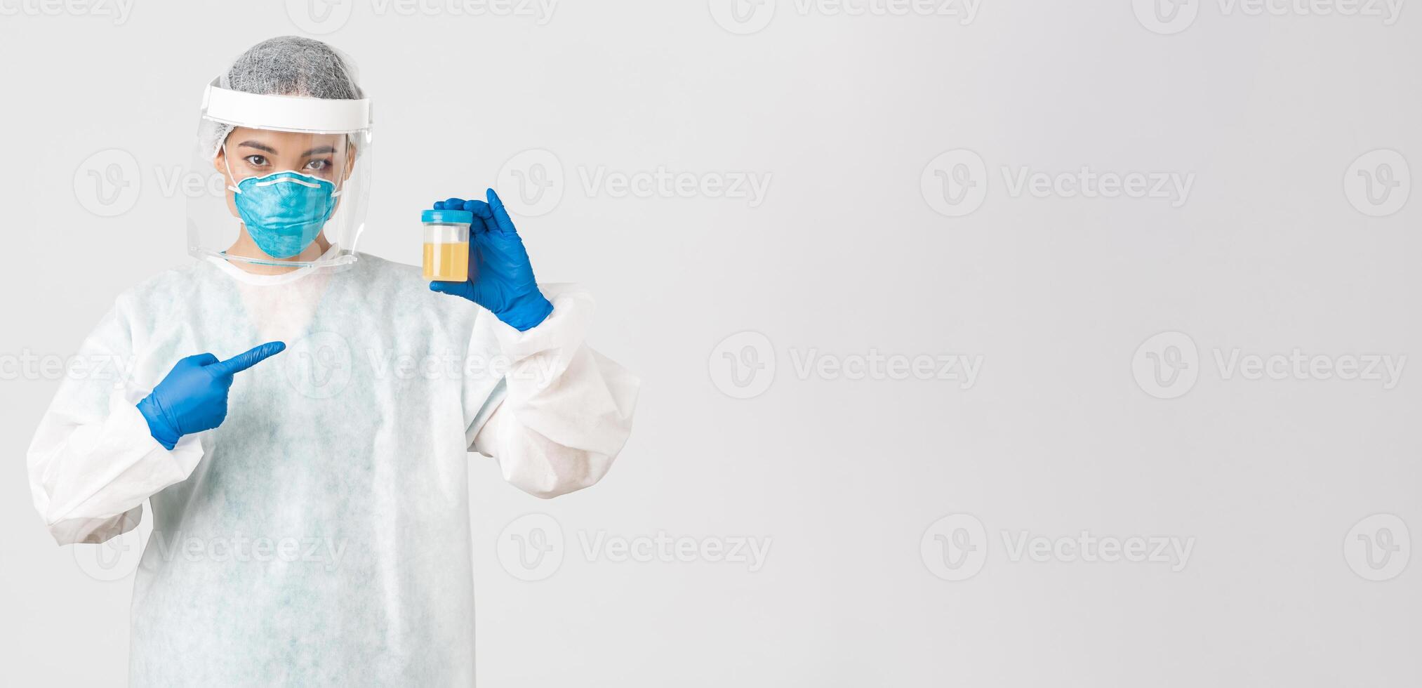 Covid-19, coronavirus disease, healthcare workers concept. Side view of serious-looking tech lab employee, researcher in personal protective equipment, pointing at urine analyze photo