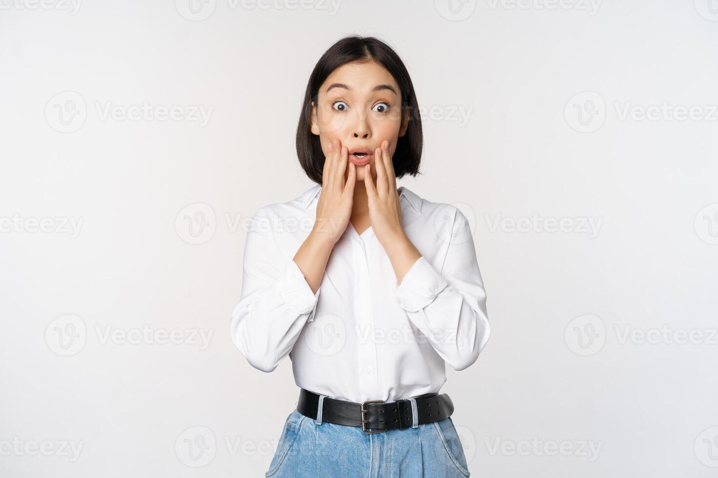 Portrait of surprised young office woman, asian businesswoman gasping amazed, saying wow, standing impressed of news against white background photo