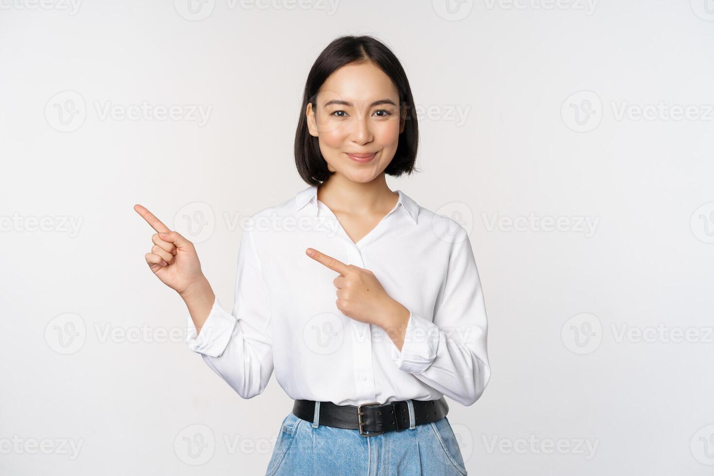 Image of smiling young office lady, asian business entrepreneur pointing fingers left, showing client info, chart of banner aside on copy space, white background photo