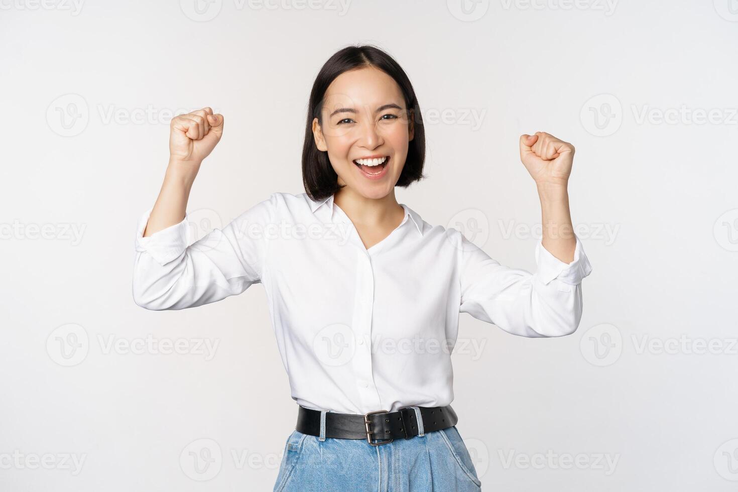 entusiasta asiático mujer alegría, decir Sí, mirando contento y celebrando victoria, campeón bailar, puño bomba gesto, en pie terminado blanco antecedentes foto