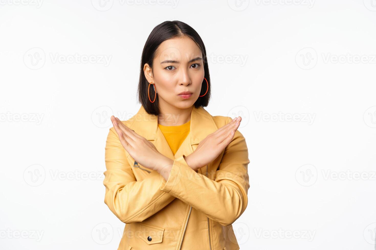 Stop gesture. Serious asian woman making arm cross, prohibit smth, rejecting, dislike and disapprove action, standing over white background photo