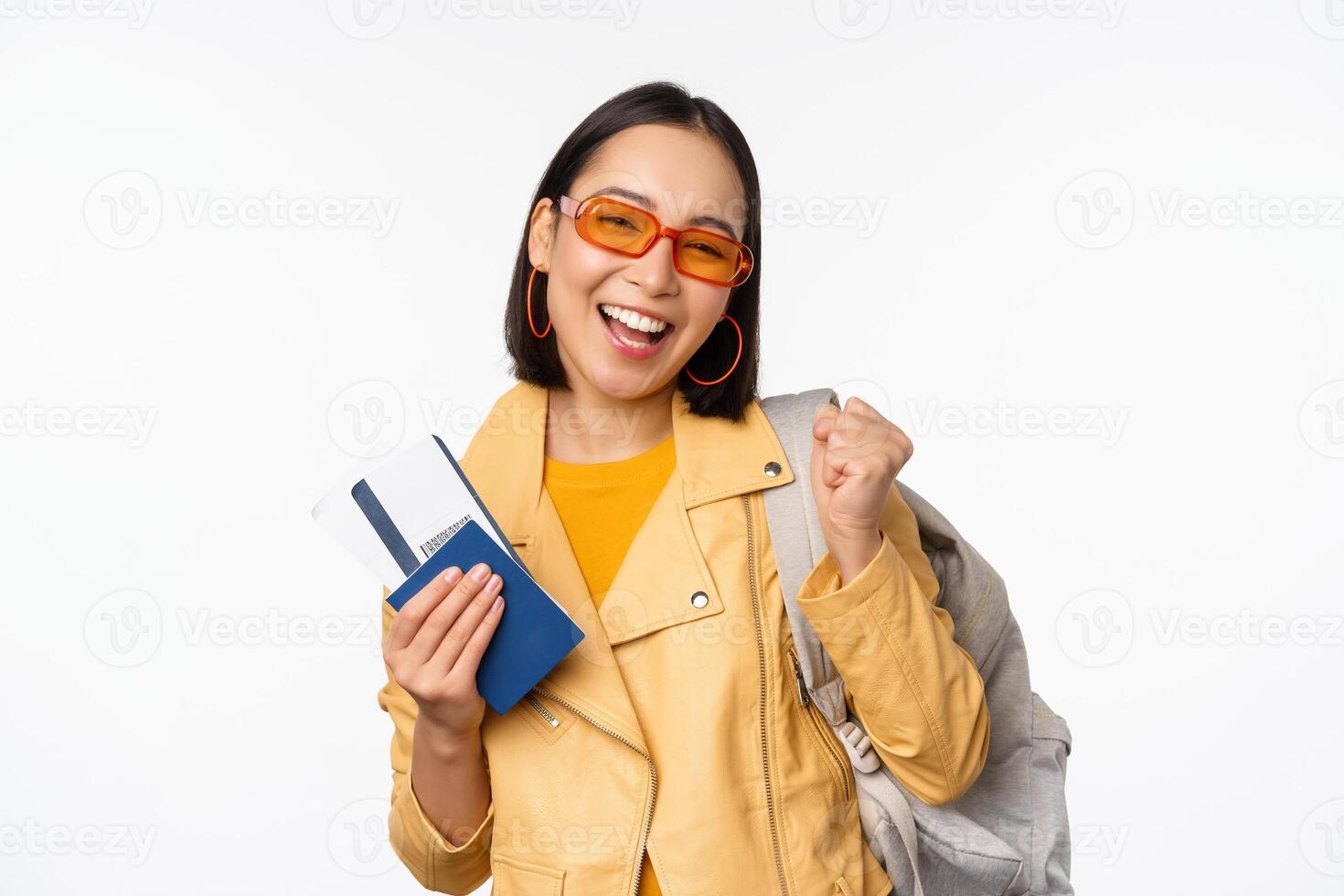 Happy asian girl going on vacation, holding passport and flight tickets, backpack on shoulder. Young woman tourist travelling abroad, standing over white background photo