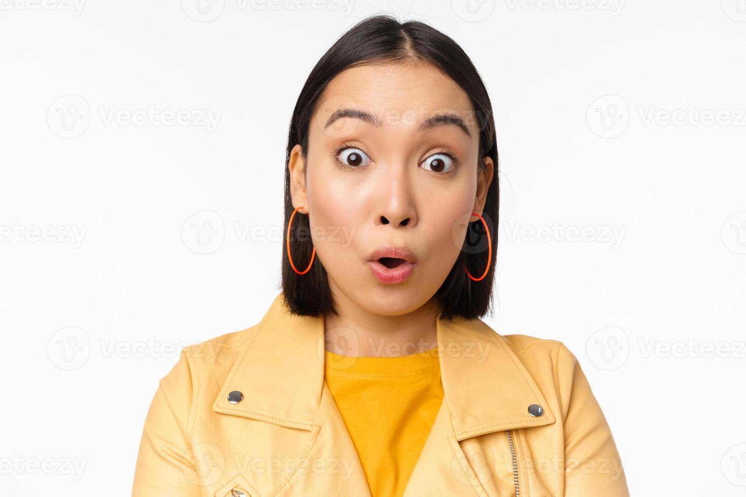 Close up of impressed asian girl, say wow, looking amazed at camera, standing in casual clothes over white background photo