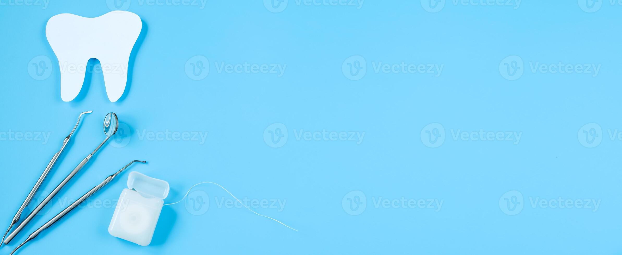 Paper cut mockup of tooth and dental instrument on blue background. Dental care concept. International Dentist Day. photo