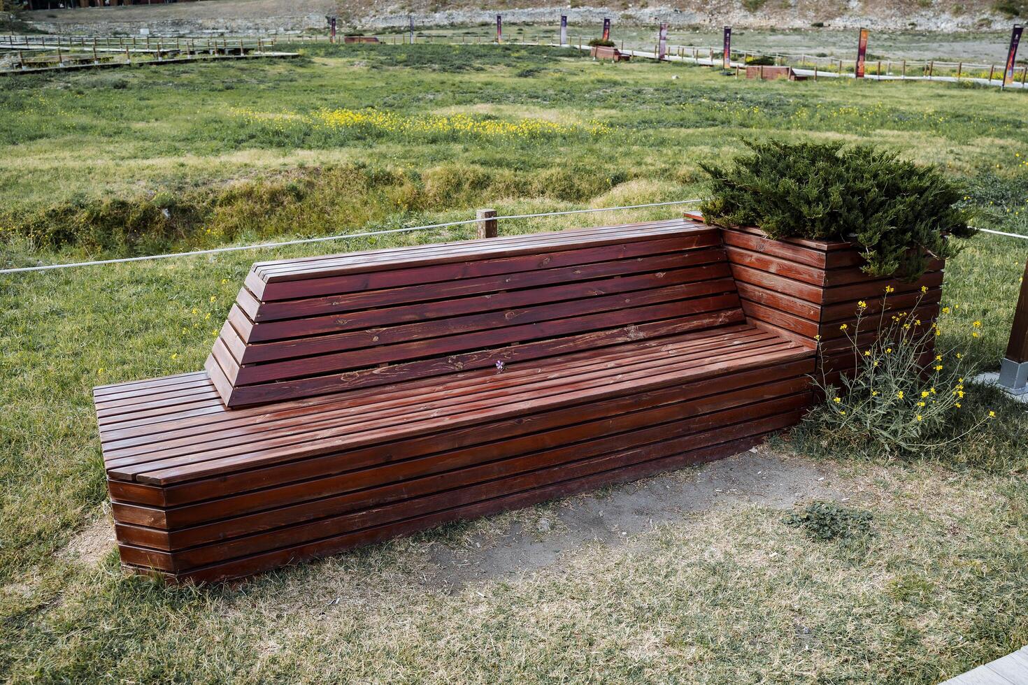 Place of rest. Wooden bench with flower garden on a green meadow. A pleasant pastime in nature. Walk, rest in summer photo