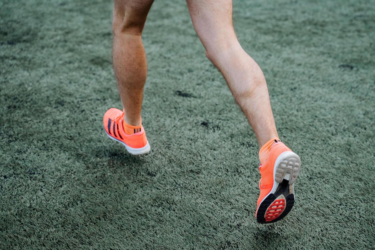 un cerca Disparo de el piernas de un corriendo hombre. activo recreación, Deportes y jugando fútbol. brillante Deportes uniforme y zapatos. atlético físico y fuerte pierna músculos. foto