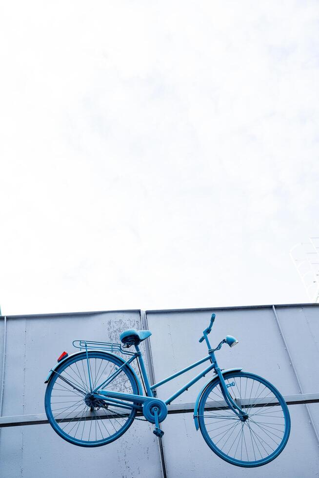 A bright blue bike is suspended from the wall. Unusual scenery on the street. Cycling. VeloLeto project in Ufa. photo