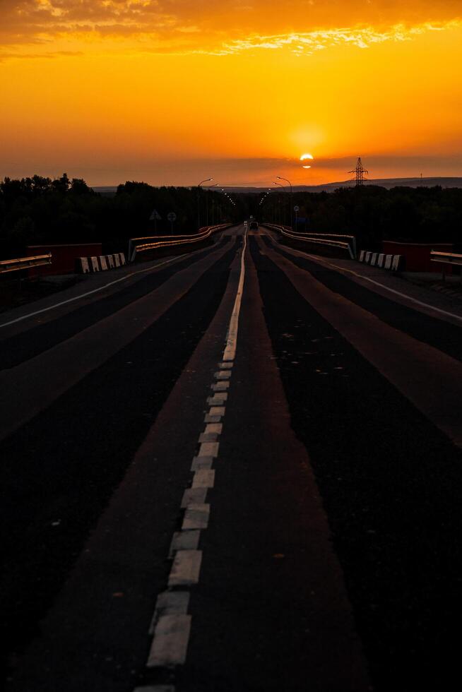 Incredibly beautiful sunset in the countryside. Bright peach and orange sunset and cumulus clouds in the sky. Sunset on the highway- photo