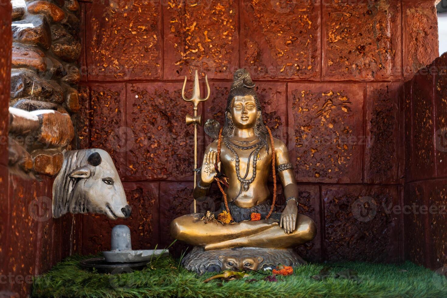 The statue of the bronze Shiva sits in the lotus position. A symbol of the Vedic culture of India. Hindu deity and cow. Place of worship of the god Shiva photo