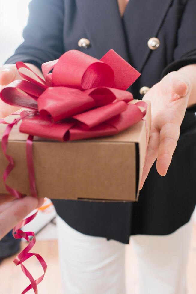 Mature woman recieving a present with red ribbon photo