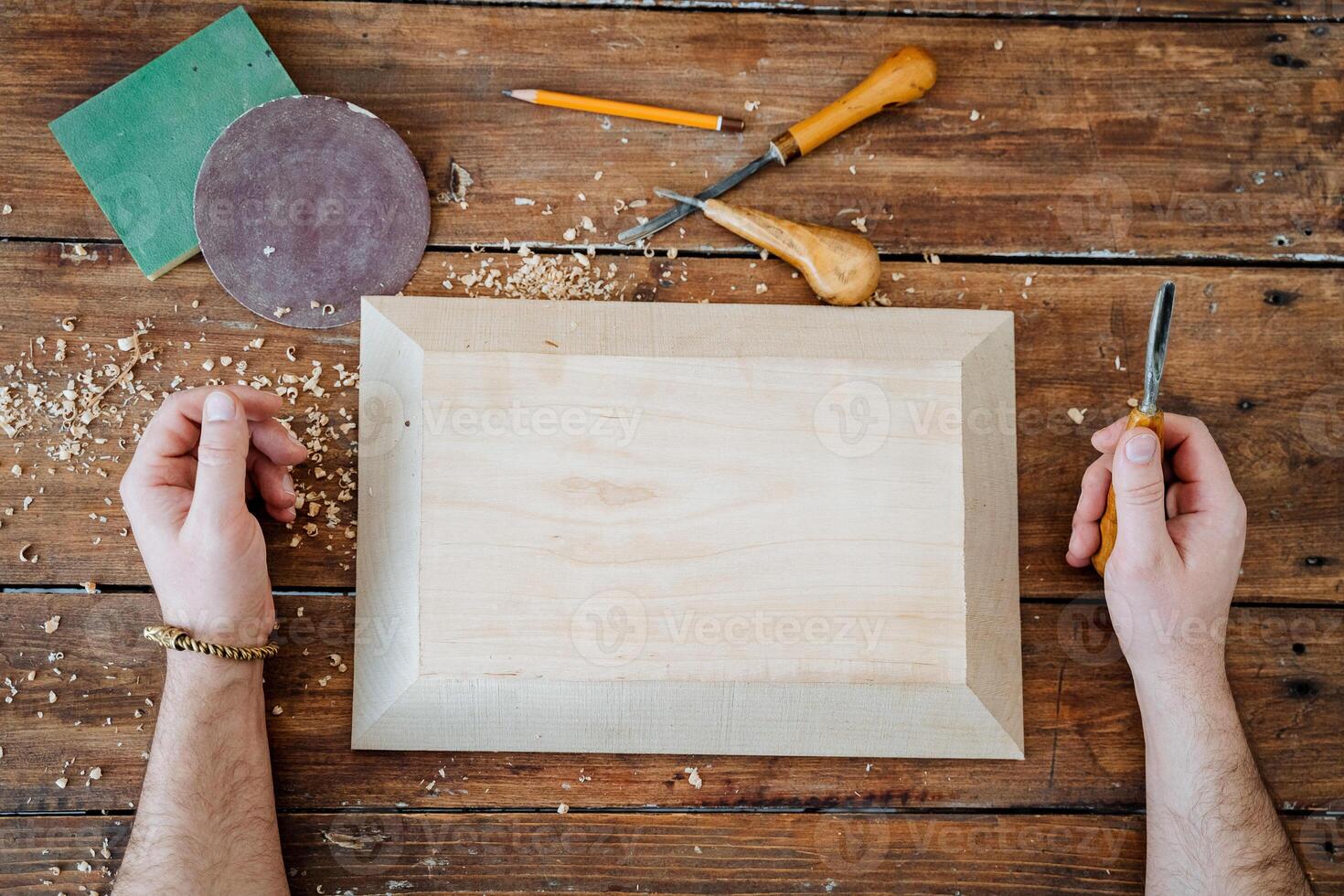 The carpenter's hands lie on a table in the workshop. White board for wood carving. Preparation with work with lumber photo