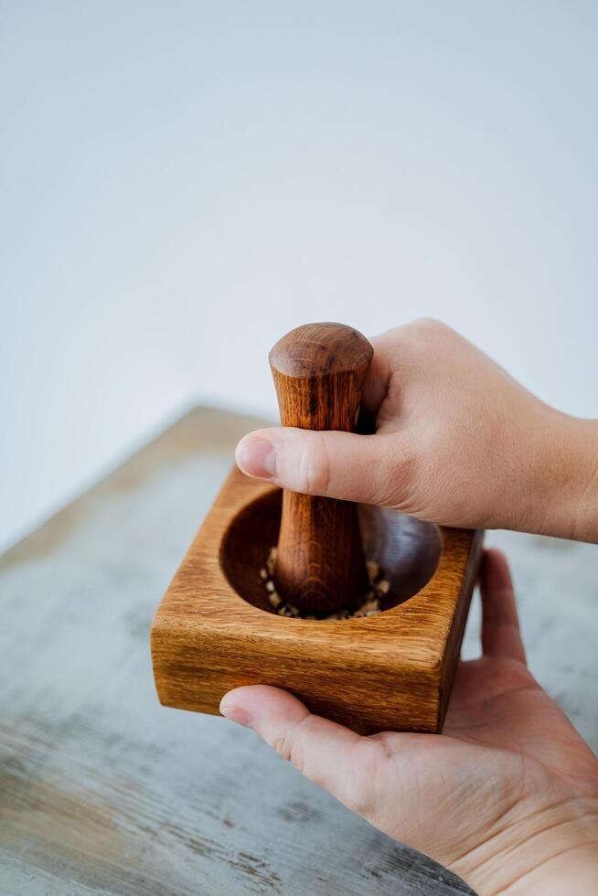hands hold a wooden stupa for spices, kitchen utensils, press your hand into crumbs, grind into flour photo