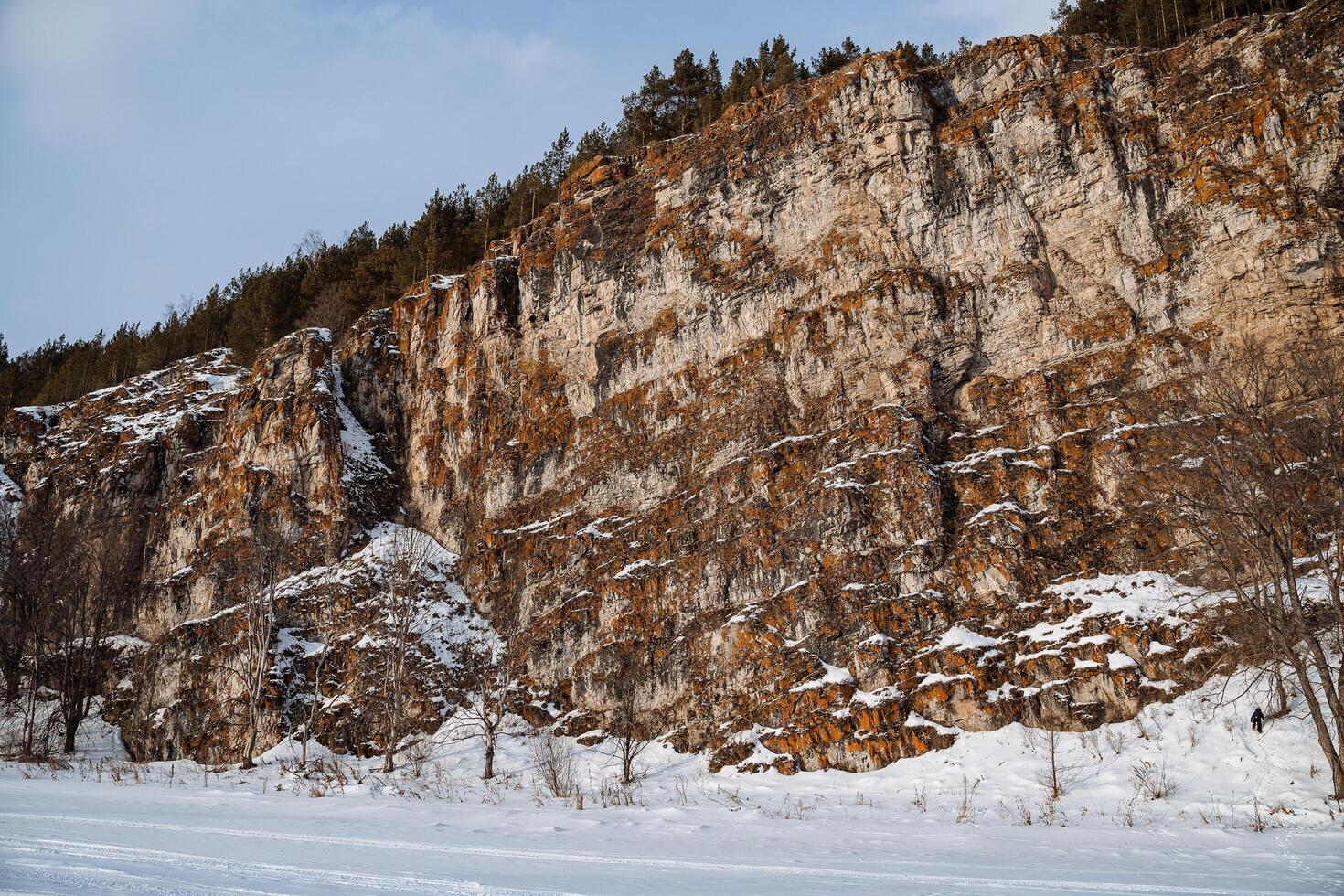 Winter in the southern Urals in the Chelyabinsk region. A frozen river against the backdrop of rocks. The flat rock is covered with orange moss. Russian Winter photo