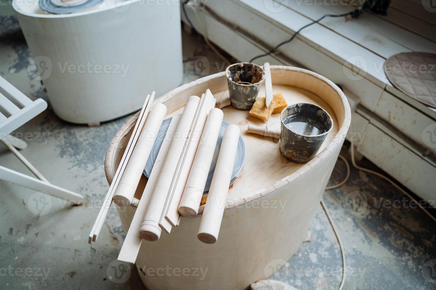 The potter's wheel with all the necessary equipment on it is removed from above. Several rolling pins and stacks lie on the potter's wheel.Engaging in creativity, creating ceramics. photo