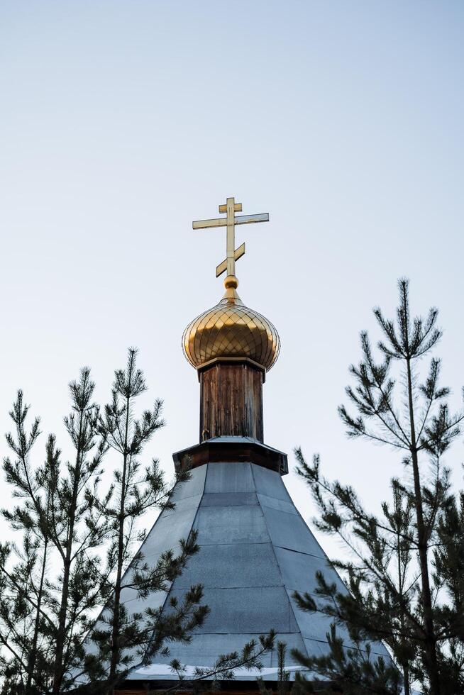 The dome churches are hidden in the forest. Golden cross on the roof of the temple. Tsasovnya standing in the forest photo