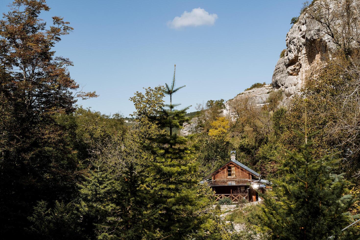 Wooden house in the forest among the mountains. Grotto in a mountainous environment. Bright sunny day in the mountains, a walk through the forest to the forester's house. Spruce and pine photo