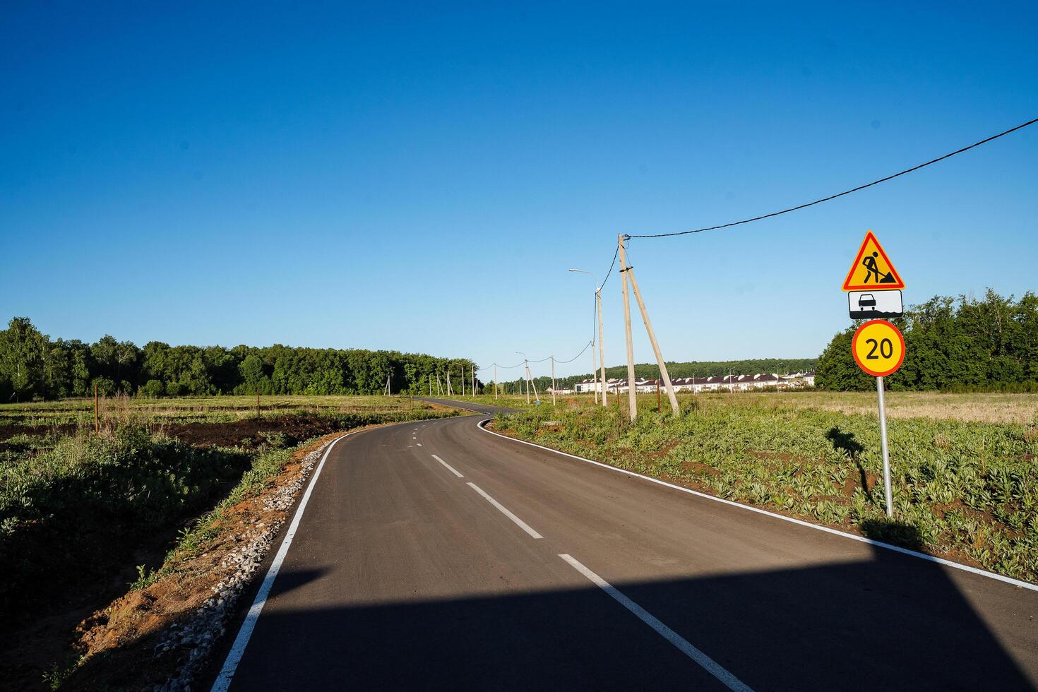 Motor road. An empty asphalt road with a bend between flower meadows in the countryside. A trip on a sunny day in summer photo