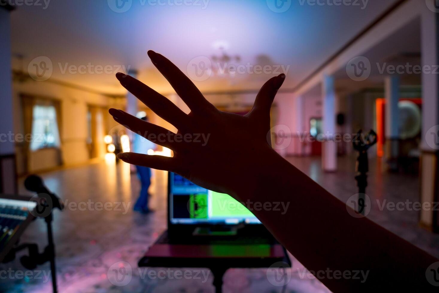 Female's hand over the dancing hall background. Recording studio mixer on digital tablet and microphone on the blurred background. Close-up hand. photo