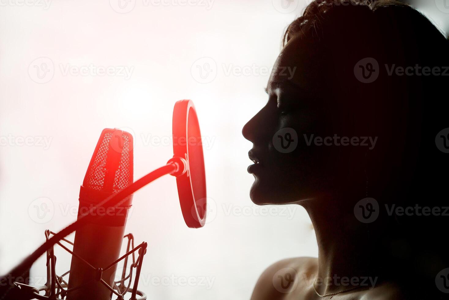 joven sensual silueta perfil con bonito cara canto a retro micrófono en blanco antecedentes. sexy mujer en frente de el mic con rojo ligero fugas en estudio. de cerca foto