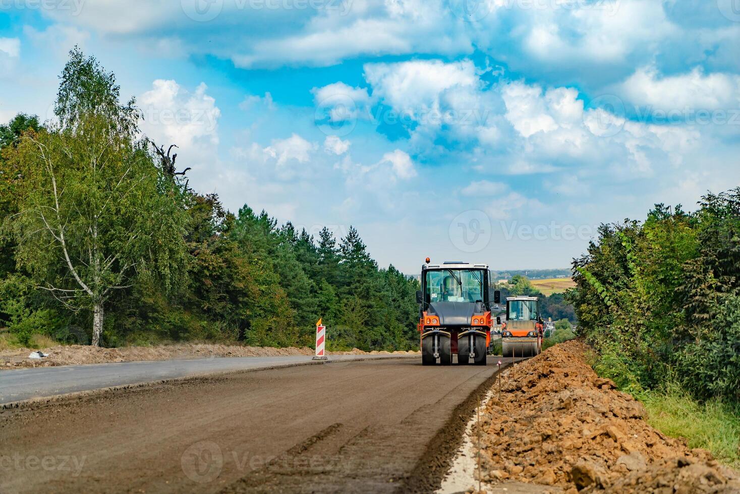 a man in orange suit prepares the road to pits repair with the help of a blower photo