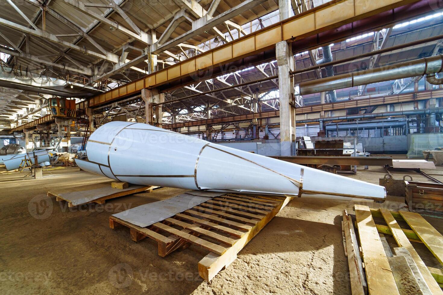 Huge tube on the background of modern engineering factory. A big construction on the wooden stand inside the factory. photo