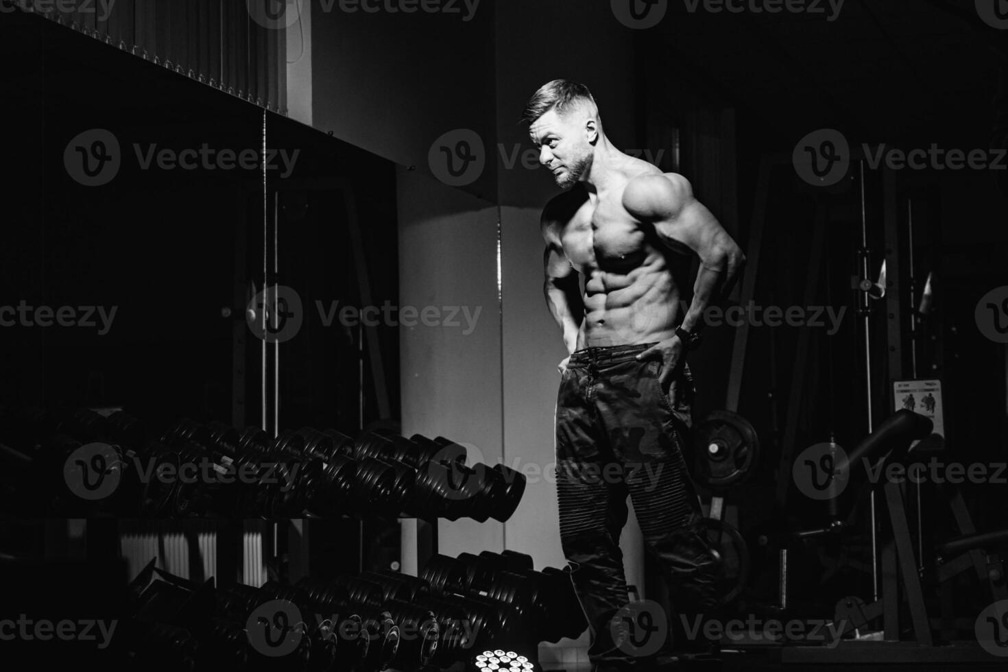 Bodybuilder showing his fit belly and biceps muscles. Athlete at gym posing at camera. Strong man flexing his muscles. Fitness concept. photo