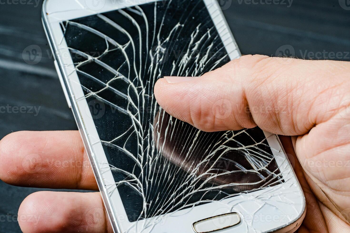 Broken phone screen in hand. Broken glass of smartphone photo